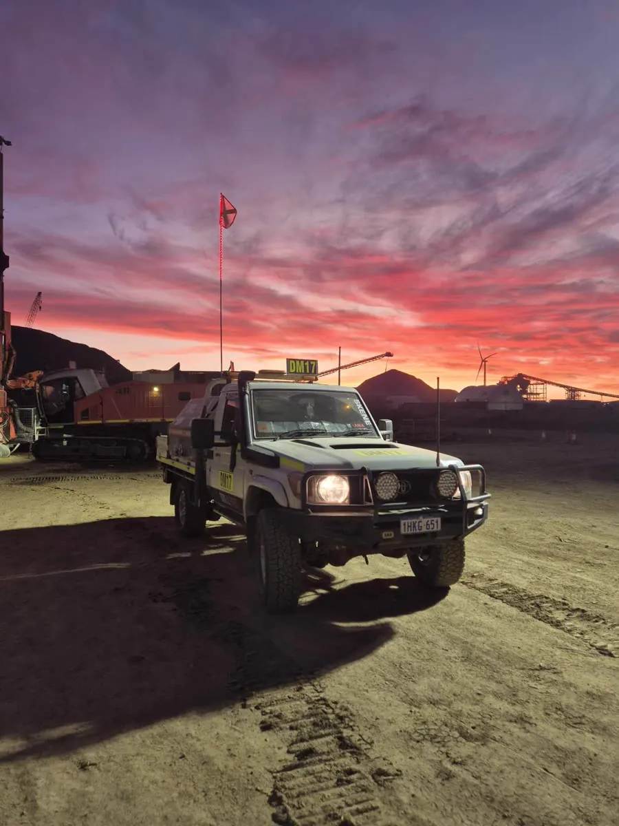 Drillspec ute front-on under a blazing pink sunrise with rigs behind