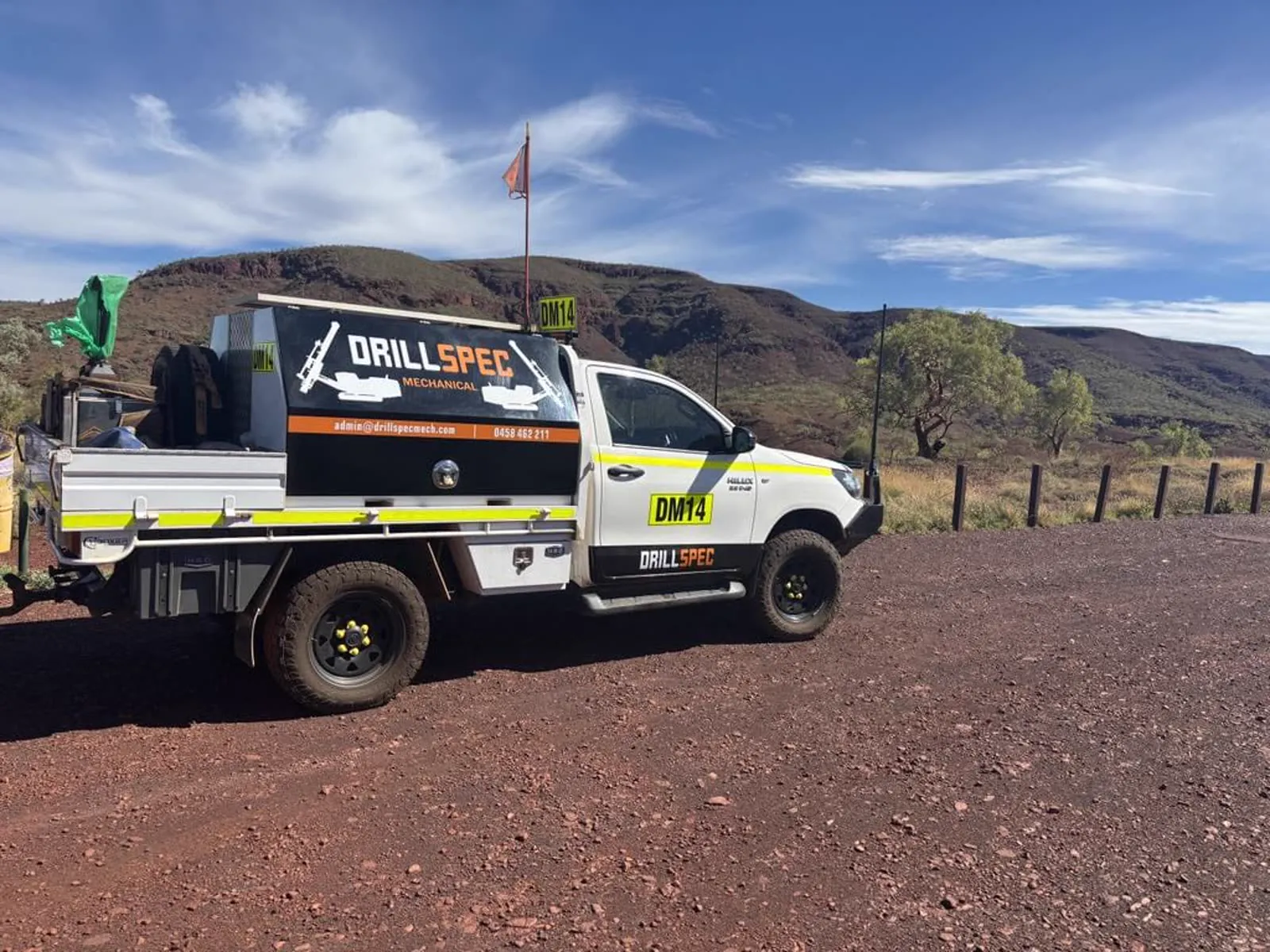 Drillspec ute on a red gravel road with ranges behind