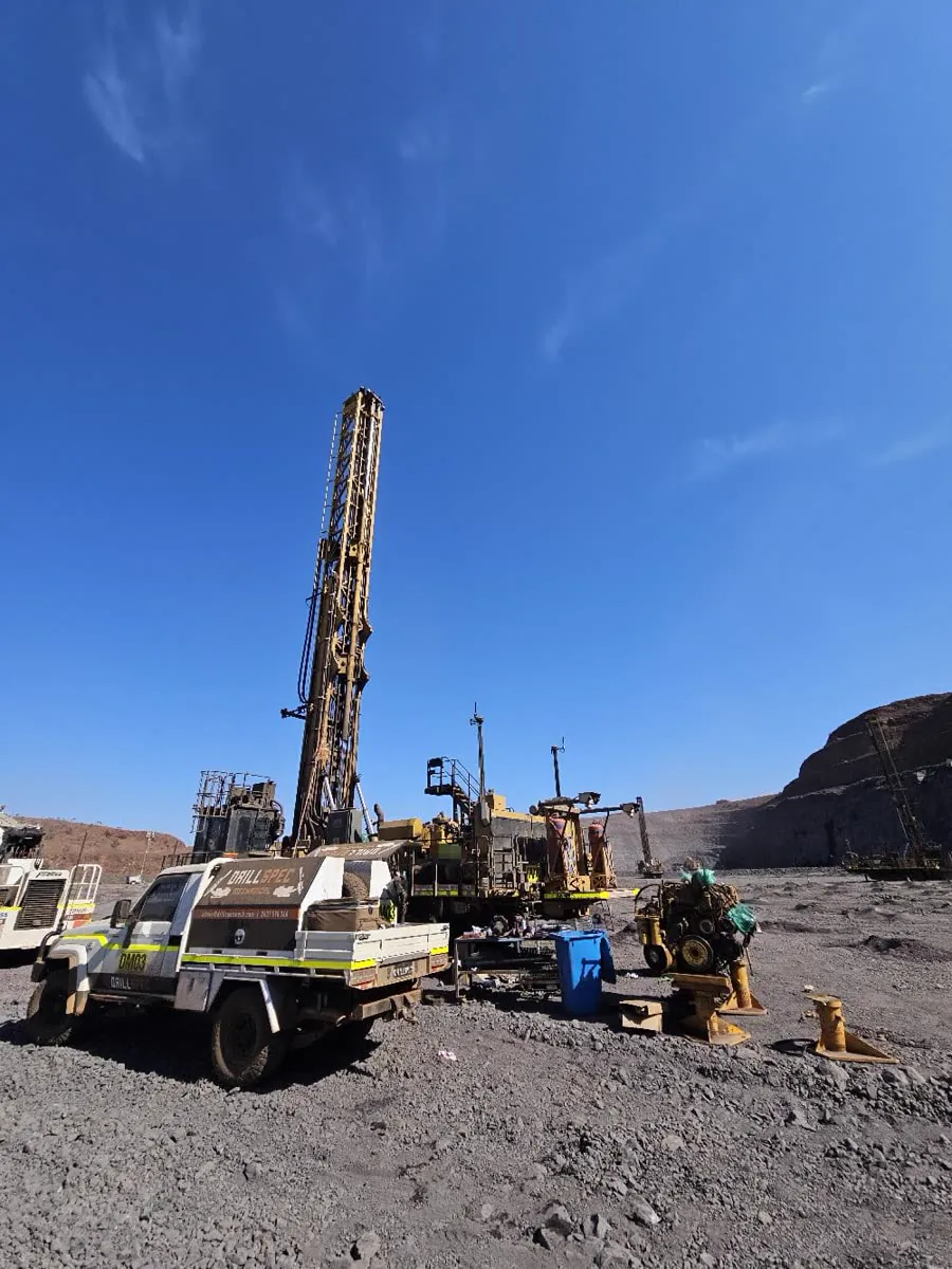Exploration drill rig and support truck under a clear blue sky