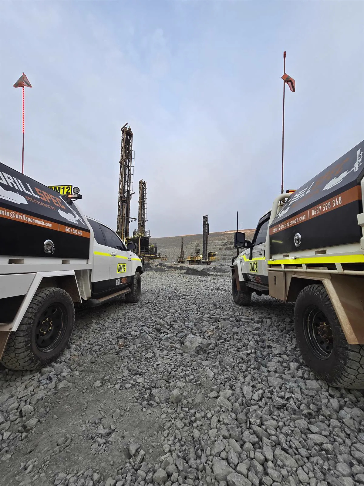Drillspec DM12 and DM03 service utes parked between drill rigs at dawn