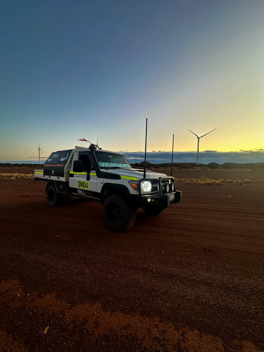 Drillspec ute at dusk with wind turbines on the horizon