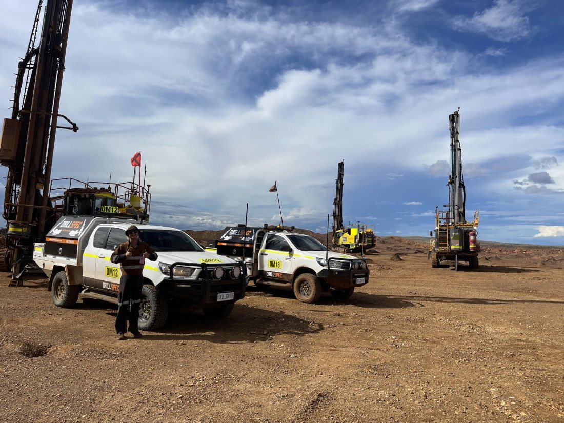 Drillspec utes and surface rigs on a Pilbara bench under dramatic cloud