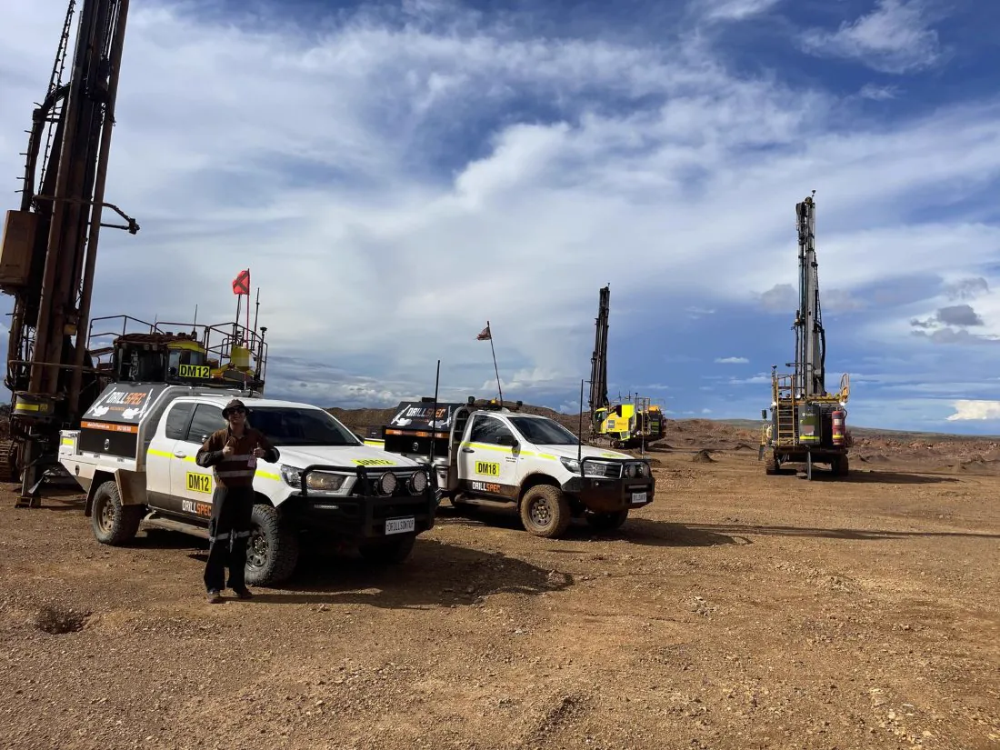 Drillspec utes and surface rigs on a Pilbara bench under dramatic cloud