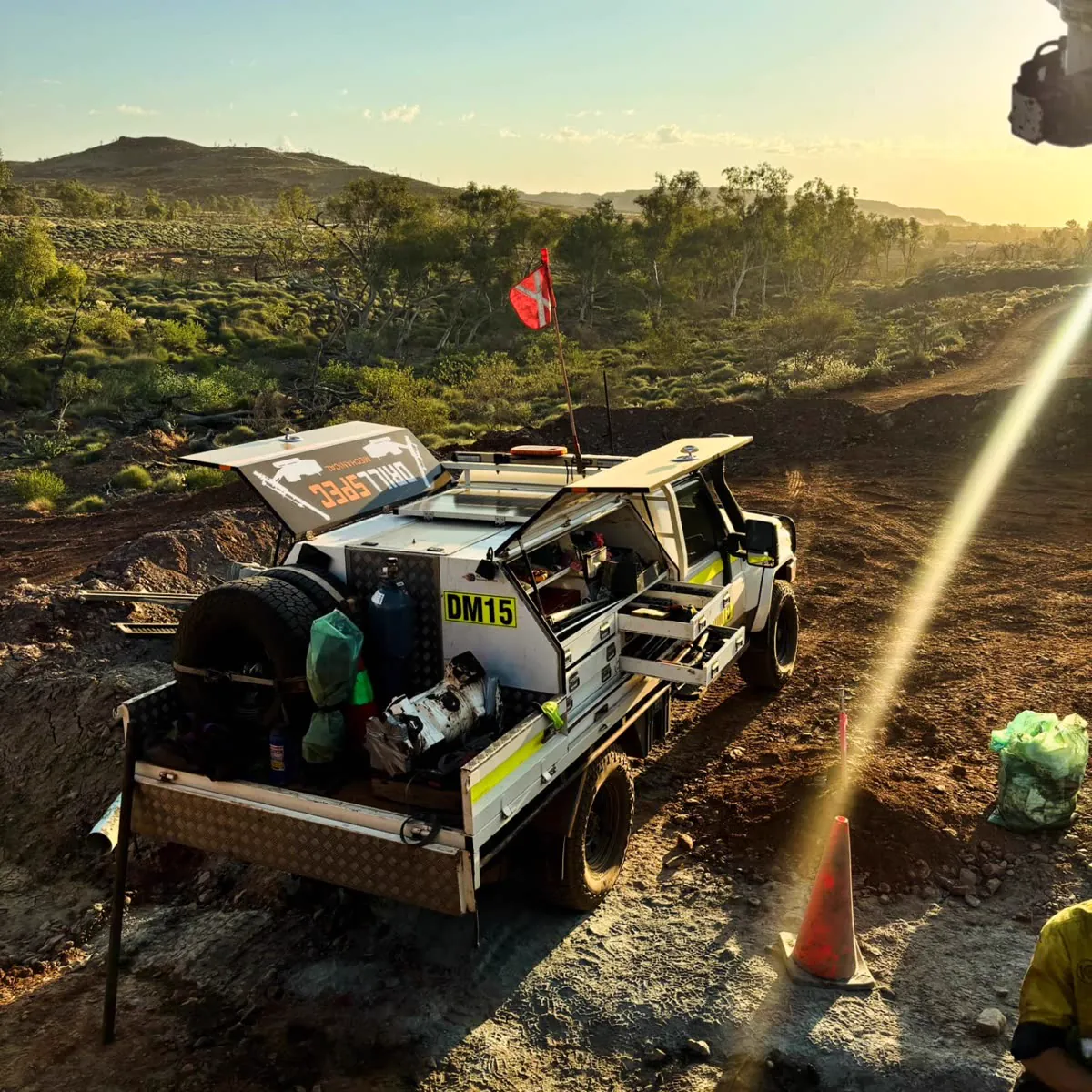 Drillspec DM15 service ute on a red-dirt track at golden hour, canopy open with the failed rotation pump on the tray