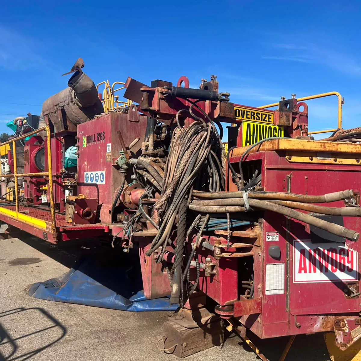The rig as it arrived — weathered deck and hydraulic hoses bundled across the frame